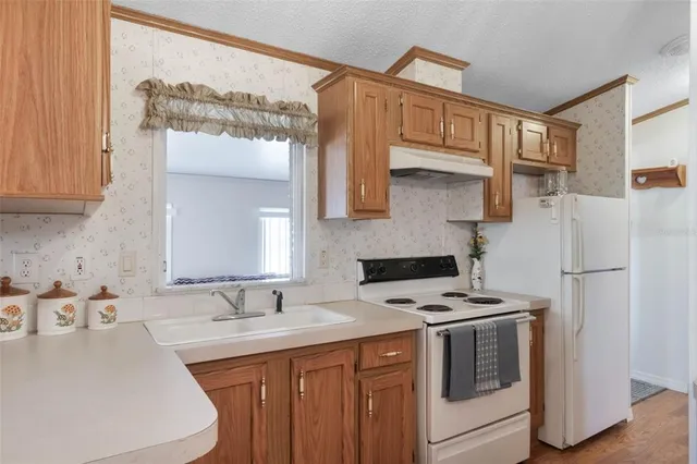 a kitchen with stainless steel appliances a refrigerator a sink and white cabinets