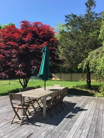 a view of backyard with table and chairs under an umbrella with trees