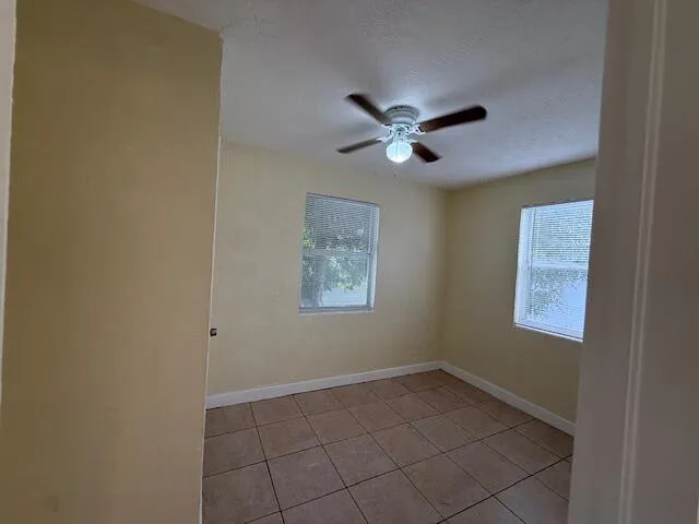 an empty room with windows and fan
