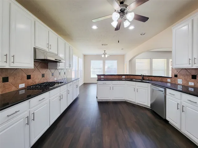 a large kitchen with cabinets wooden floor and stainless steel appliances