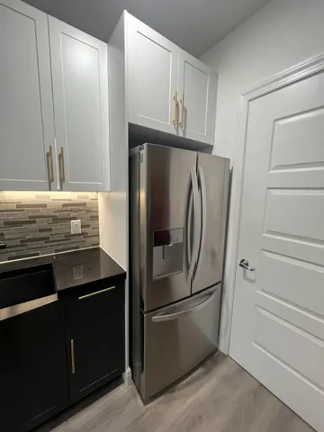 a view of a refrigerator in kitchen and an empty room