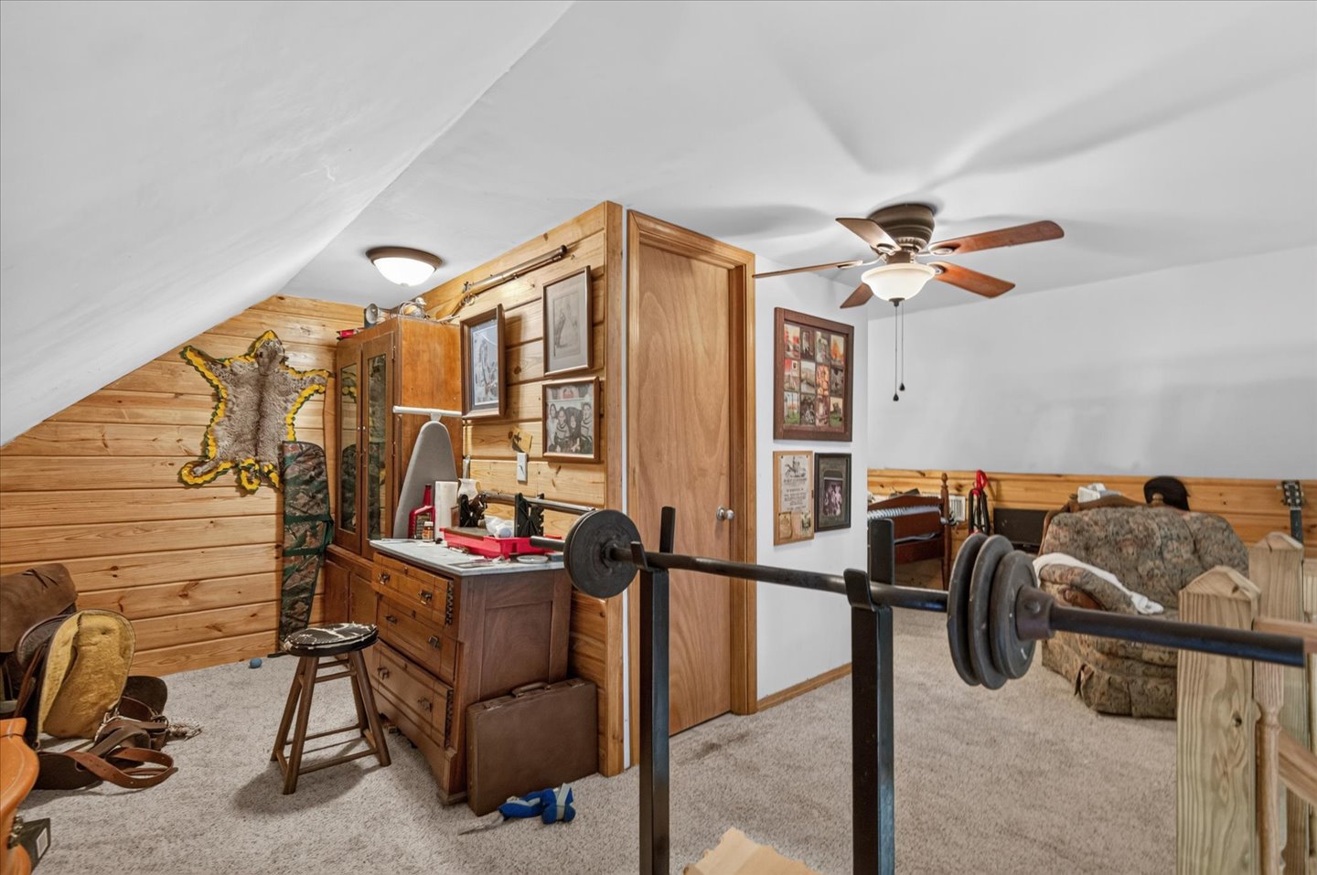 26115 4157th Road Nowata, OK 74048 - Photo 21 of 36 Sloped ceilings, wood-paneled accent wall, neutral carpeting, and a ceiling fan with light fixture