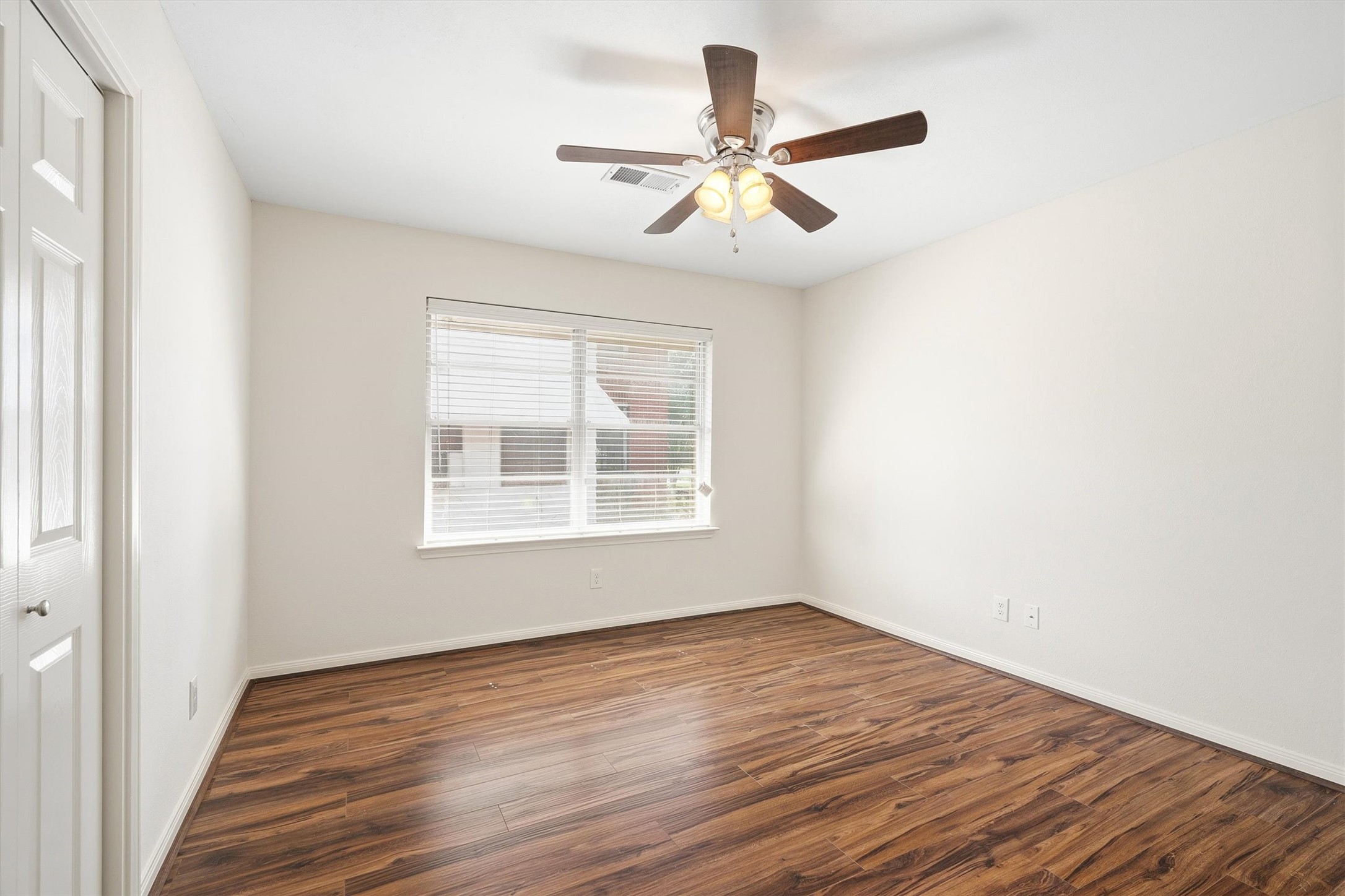 3331 Arbor Street Houston, TX 77004 - Photo 18 of 30 This bedroom features fresh white walls, rich wooden flooring, and a large window for natural light. It includes a ceiling fan with lights and a closet, offering a bright and inviting space.