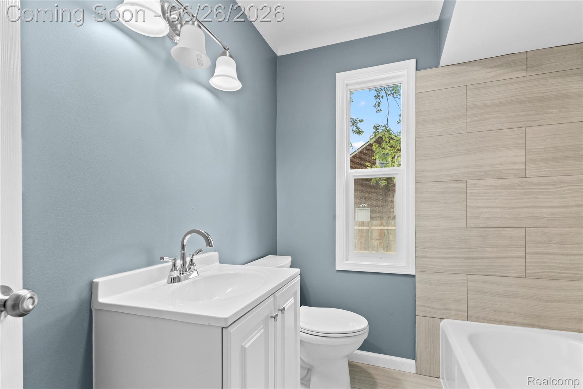 8310 Whitcomb Detroit, MI 48228 - Photo 17 of 26 Full bathroom featuring a white vanity with integrated sink, chrome faucet, and a three-light vanity fixture