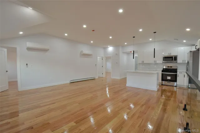a view of kitchen with kitchen island a sink wooden floor and stainless steel appliances