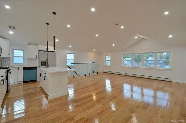 a view of a kitchen with kitchen island a sink wooden floor and a refrigerator