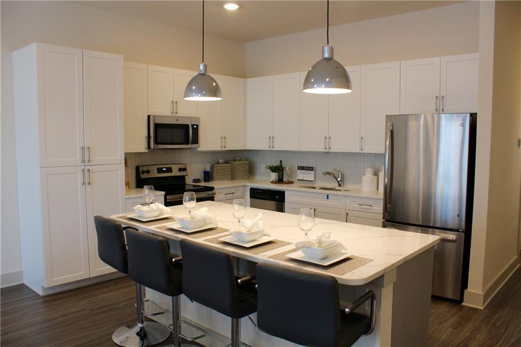 a kitchen with stainless steel appliances granite countertop a sink a stove a refrigerator and cabinets
