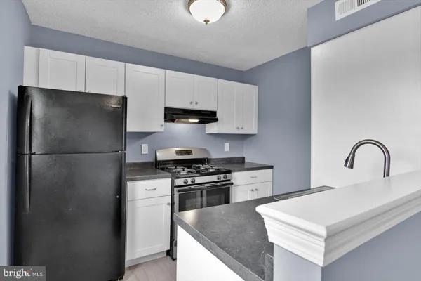 a kitchen with stainless steel appliances granite countertop a refrigerator sink and white cabinets