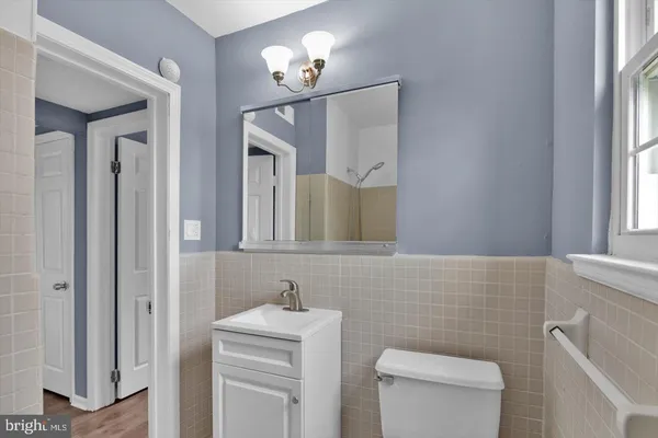 a bathroom with a toilet a sink a mirror a window and vanity