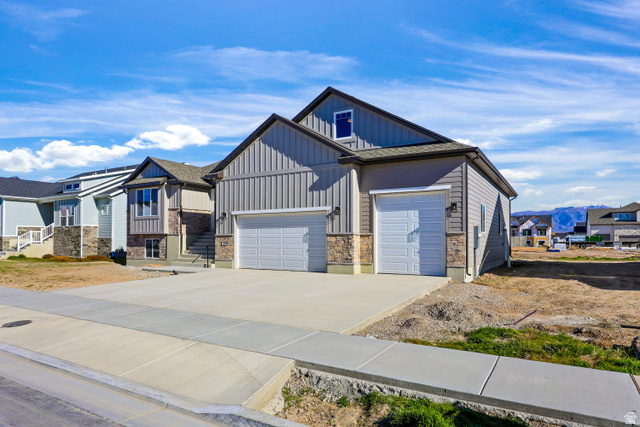 1139 South 4475 West West Point, UT 84015 - Photo 2 of 33 View of front of home featuring board and batten siding, concrete driveway, stone siding, a residential view, and a mountain view