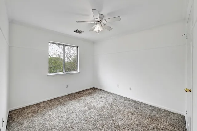 an empty room with a window and a fan