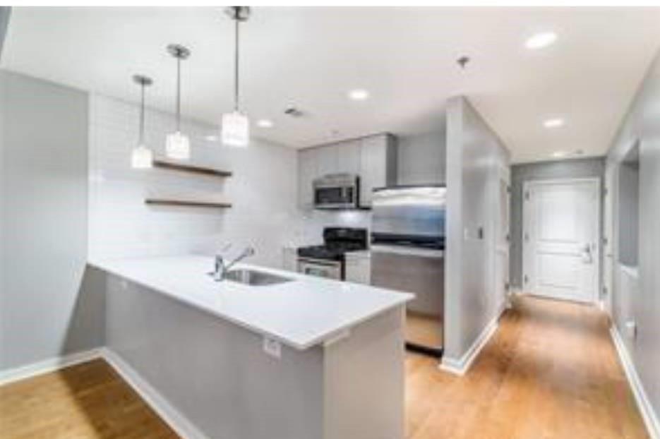 a kitchen with kitchen island a sink stainless steel appliances and a counter top space