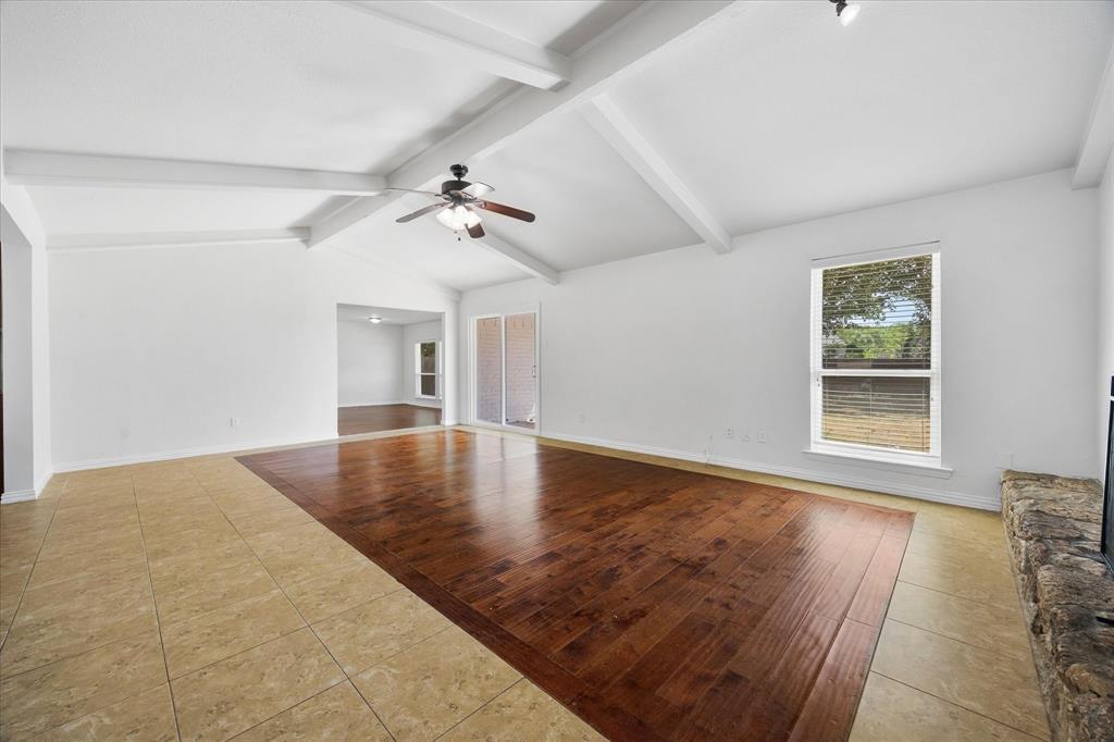 925 Lake North Road Rowlett, TX 75089 - Photo 12 of 37 Vaulted ceiling with exposed beams, wood-finish flooring, tile flooring, ceiling fan with light fixture, and a stone-clad hearth