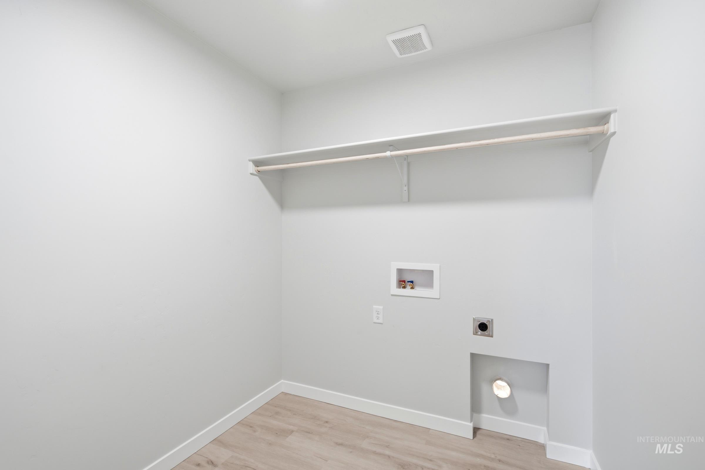 13324 Bank Street Caldwell, ID 83607 - Photo 24 of 29 Utility space featuring wood-finish flooring, a wall-mounted shelf, and a clothing rod