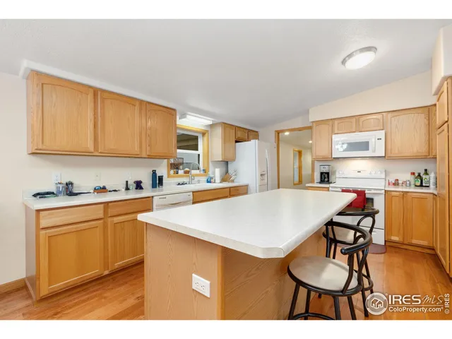 a kitchen with stainless steel appliances granite countertop a sink a stove a refrigerator a microwave oven with white cabinets and wooden floor