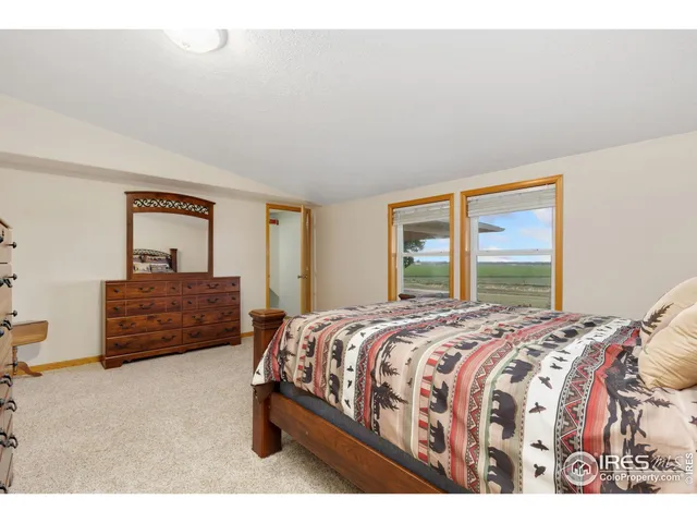 a bedroom with a bed a dresser and next to a window