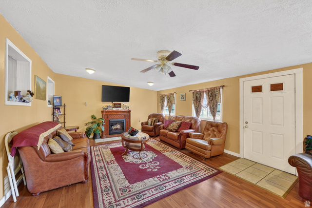 977 23rd Street Ogden, UT 84401 - Photo 18 of 29 Living room featuring light wood-type flooring, ceiling fan, a glass covered fireplace, and a textured ceiling