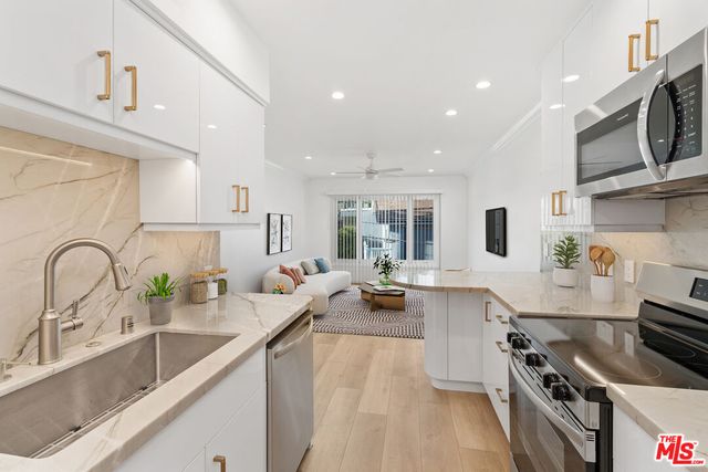 a large kitchen with stainless steel appliances a sink a stove and cabinets