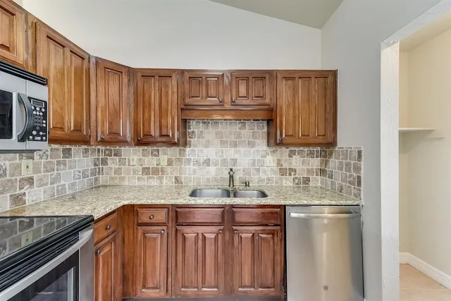 a kitchen with stainless steel appliances granite countertop a sink dishwasher stove and cabinets with wooden floor