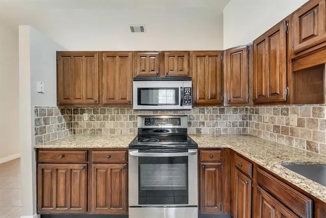 a kitchen with granite countertop a stove top oven microwave and cabinets