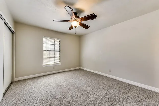 an empty room with ceiling fan and windows