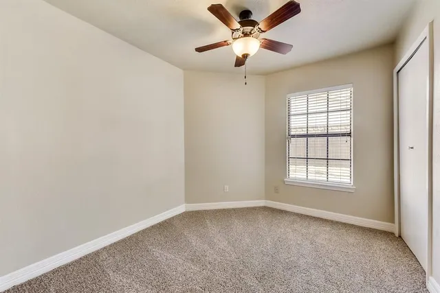 an empty room with a window and a fan