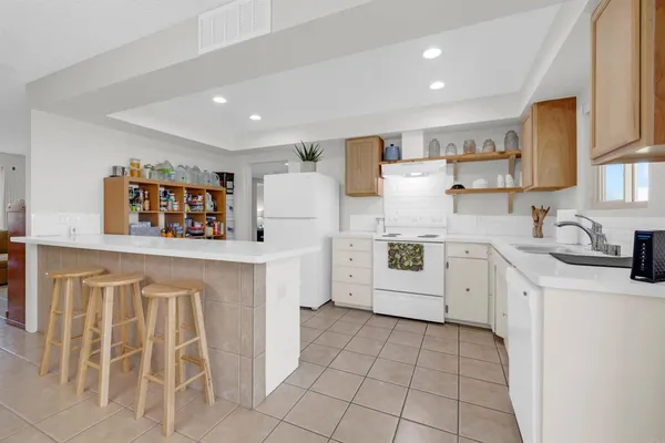 a kitchen with white cabinets a sink stove and refrigerator