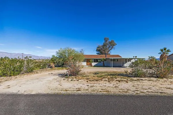 a view of a dry yard with a house in the background