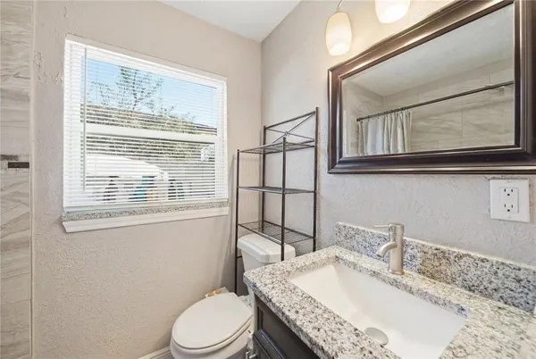 a bathroom with a granite countertop toilet sink and mirror