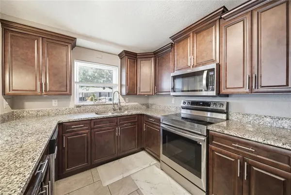 a kitchen with stainless steel appliances granite countertop wooden cabinets a stove top oven and a granite counter top