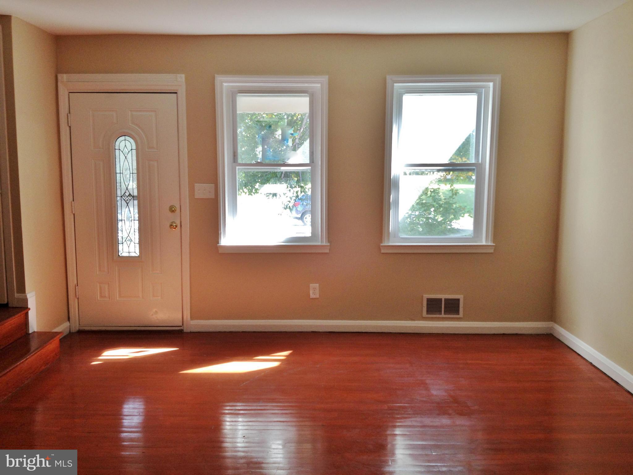 8328 Ridgely Oak Road Parkville, MD 21234 - Photo 2 of 10 an empty room with wooden floor and windows