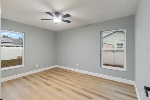 an empty room with windows and a ceiling fan
