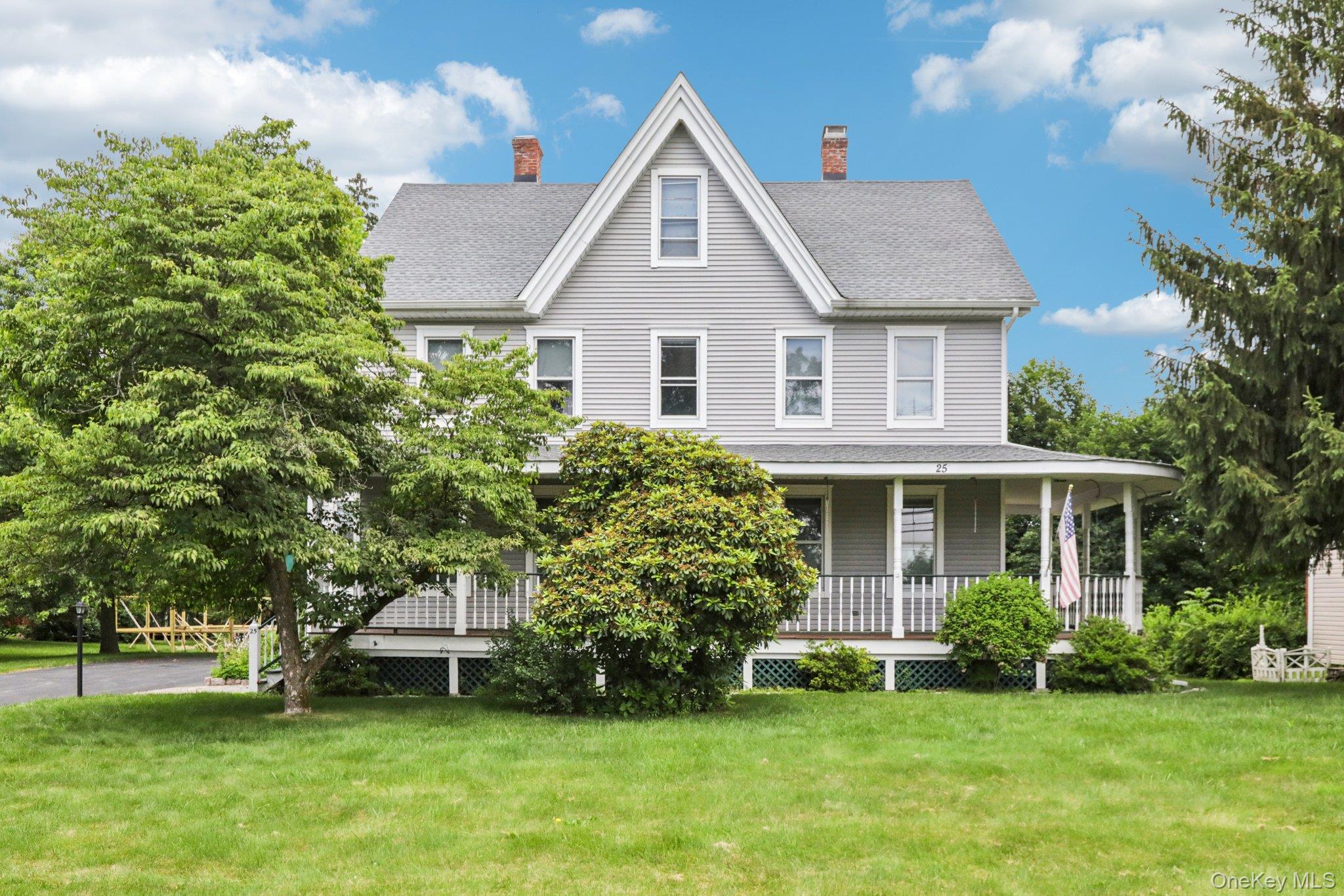 Farmhouse inspired home with a porch, a front yard, a chimney, and a shingled roof