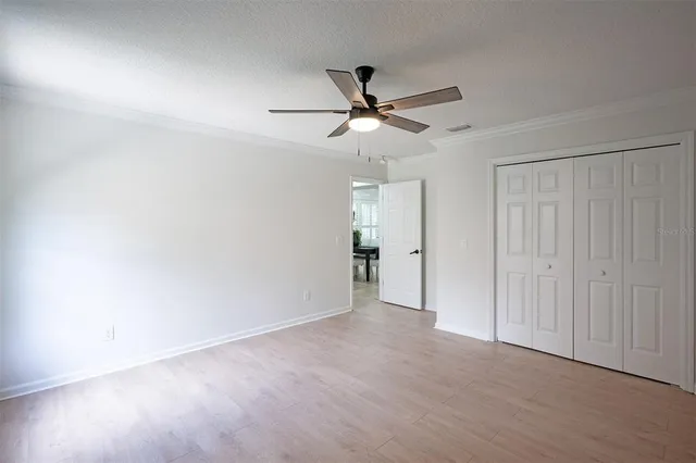 an empty room with chandelier fan and windows