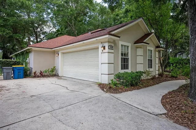 a view of a white house with a yard and large tree