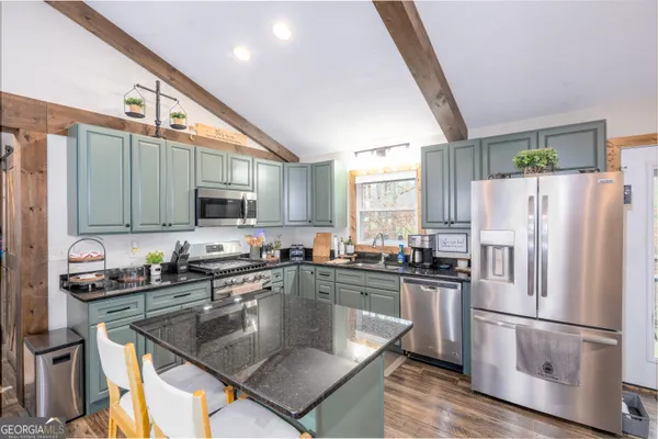 a kitchen with stainless steel appliances granite countertop a sink a stove and a refrigerator