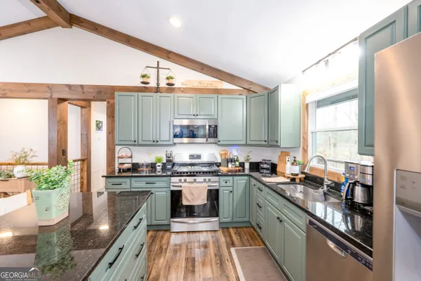 a kitchen with stainless steel appliances granite countertop a stove a sink and a refrigerator