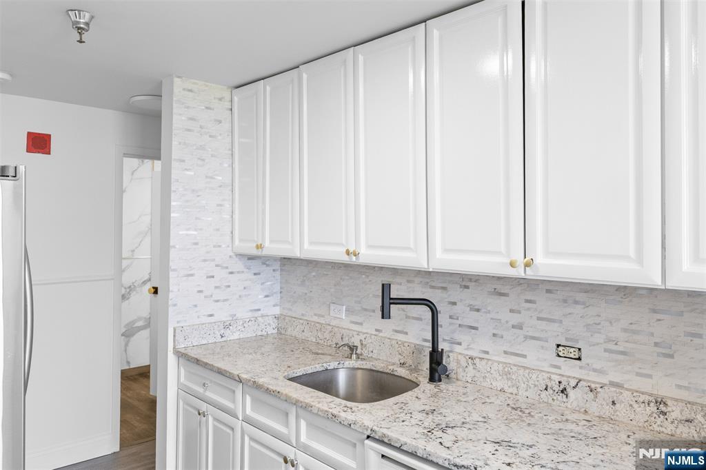 100 Old Palisade Road, Unit 3215 Fort Lee, NJ 07024 - Photo 18 of 43 a kitchen with stainless steel appliances granite countertop a sink dishwasher a refrigerator and white cabinets with wooden floor