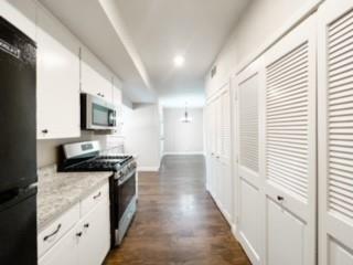 4512 Sycamore Street Dallas, TX 75204 - Photo 15 of 23 Kitchen featuring appliances with stainless steel finishes, white cabinets, dark wood-style flooring, and pendant lighting