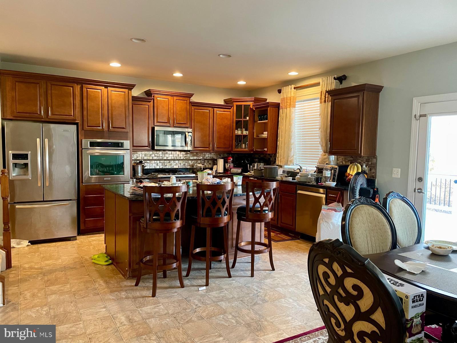 22225 Falling Terrace Ashburn, VA 20148 - Photo 18 of 30 a kitchen with stainless steel appliances granite countertop a table chairs and a refrigerator