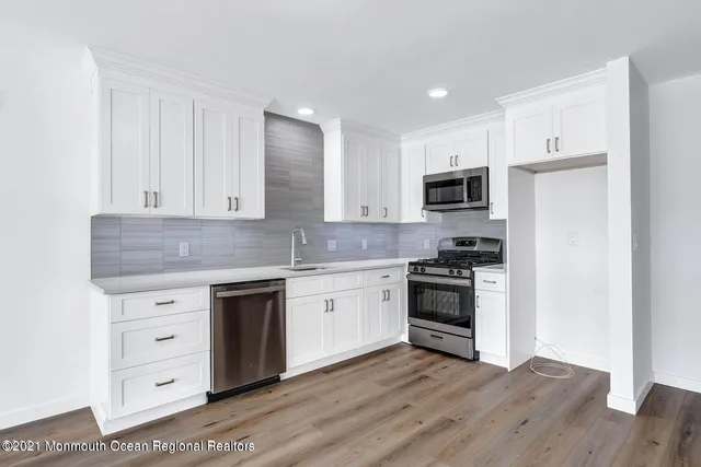 a kitchen with granite countertop white cabinets and stainless steel appliances