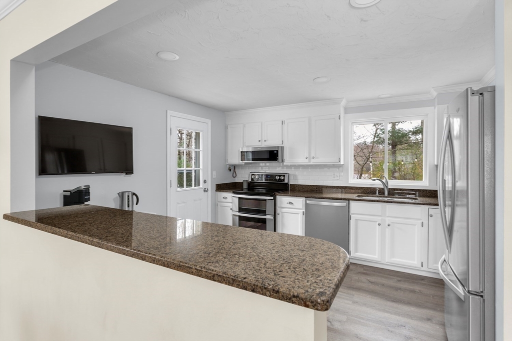 7 Glenwood Road Franklin, MA 02038 - Photo 7 of 46 a kitchen with granite countertop a sink and a stove top oven with wooden floor