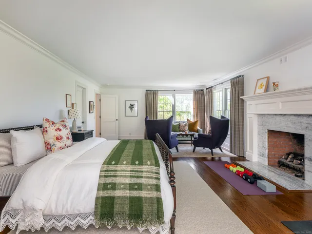 a bedroom with a bed a table and a fireplace