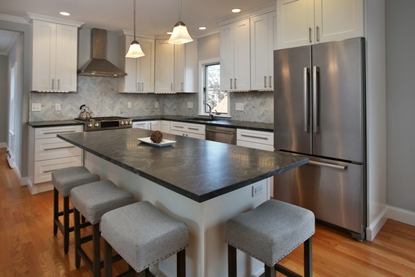 a kitchen with stainless steel appliances granite countertop a table chairs refrigerator and microwave