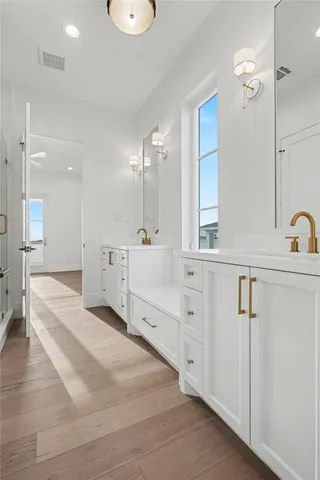 a large white bathroom with a double vanity sink a mirror and a bathtub