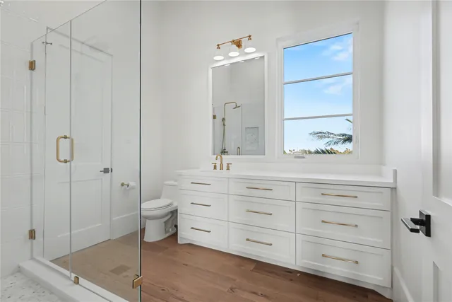 a bathroom with a double vanity sink a toilet and shower