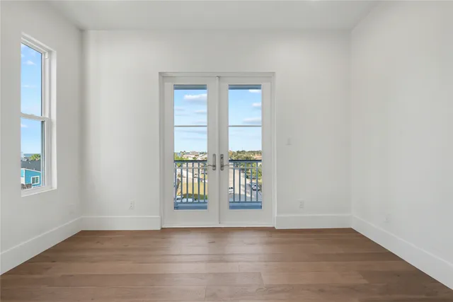 an empty room with wooden floor and balcony