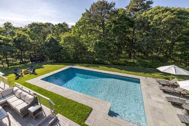 a view of swimming pool with lawn chairs under an umbrella