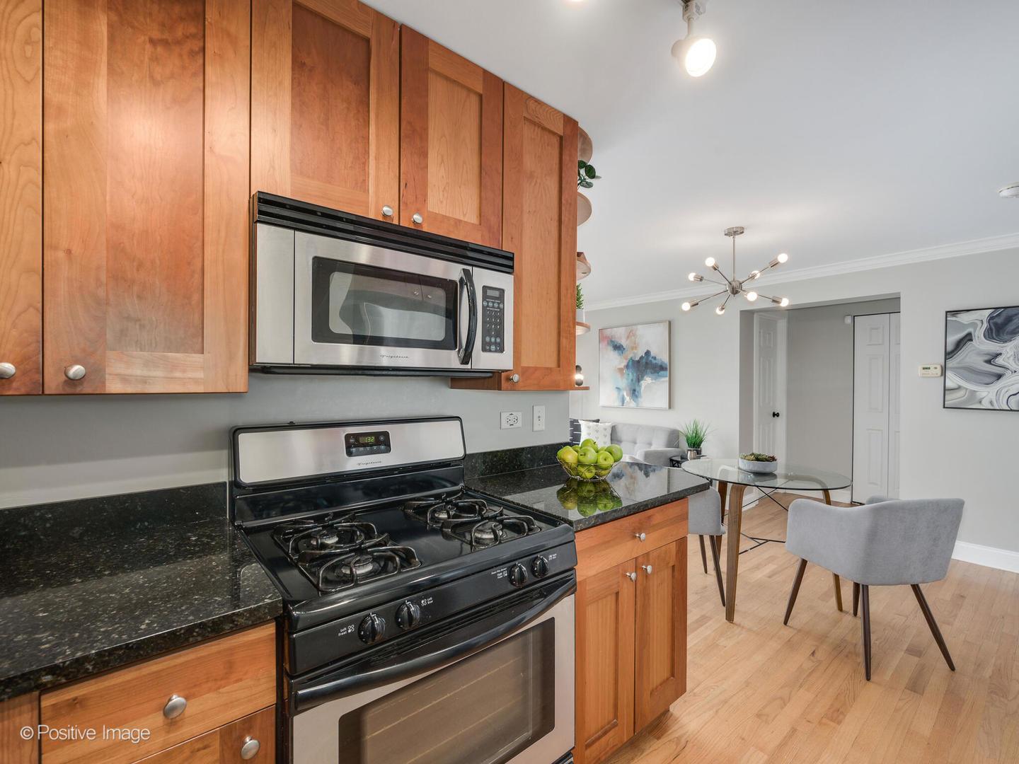 4144 North Sheridan Road, Unit 203 Chicago, IL 60613 - Photo 7 of 15 a kitchen with granite countertop wooden cabinets and stainless steel appliances