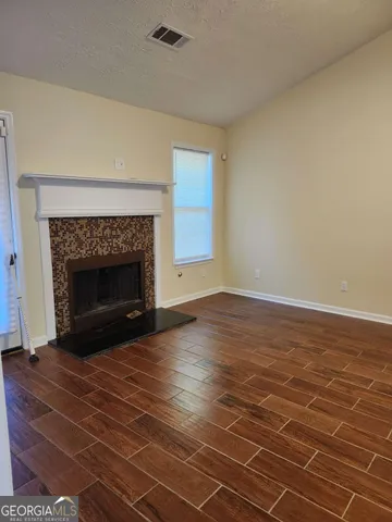 a view of empty room with wooden floor and fireplace
